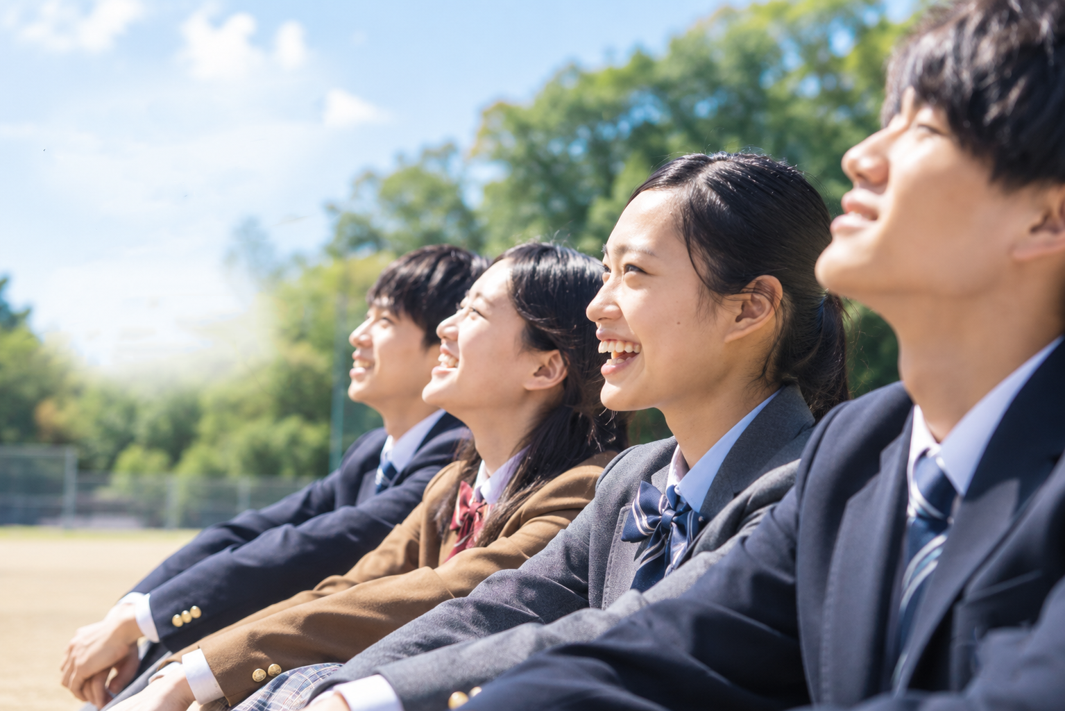 制服姿の高校生たちが屋外で笑顔を見せている様子